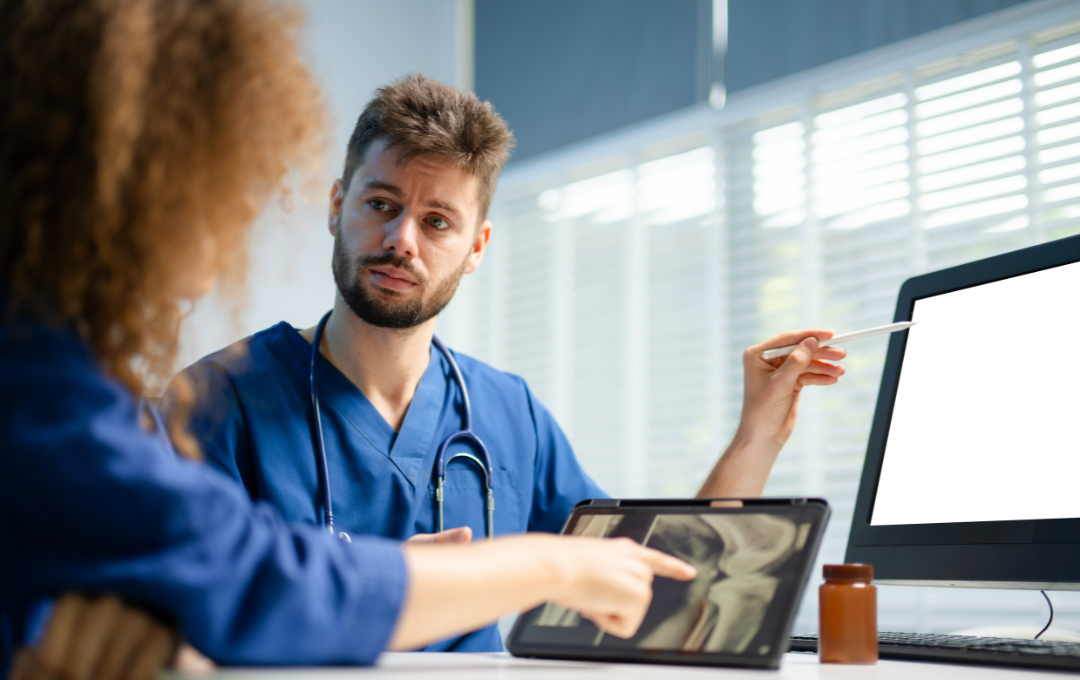Knee pain specialist presenting X-ray image of the patient's knee as he describes how genicular artery embolization and radiofrequency ablation work.