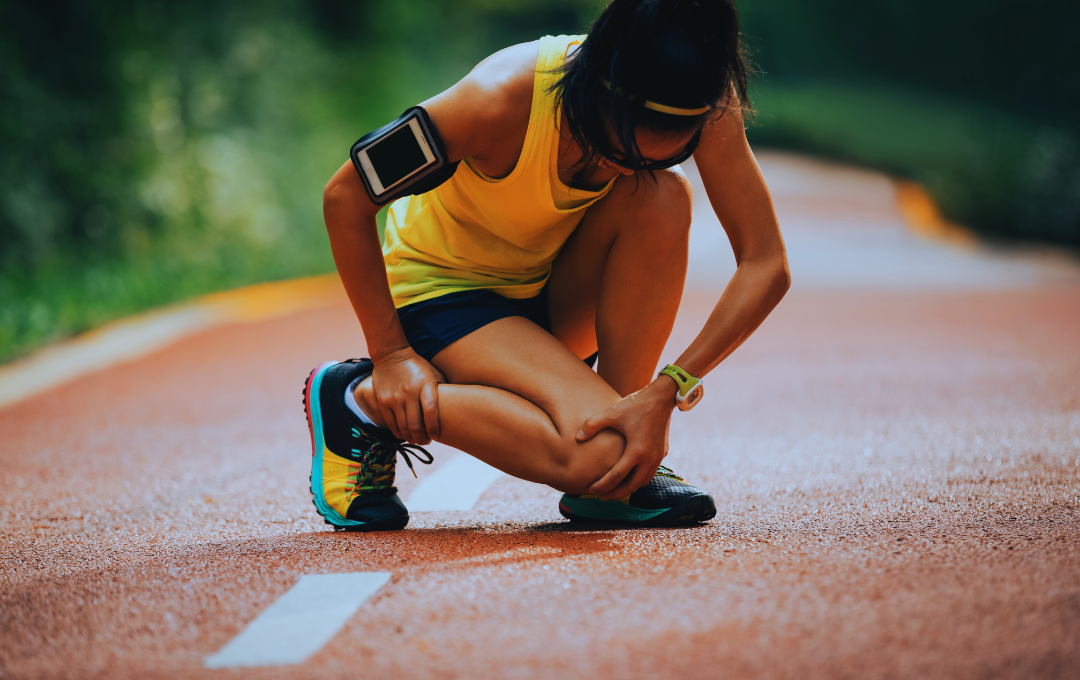 A woman stopping in the middle of her run due to pain in her knee.