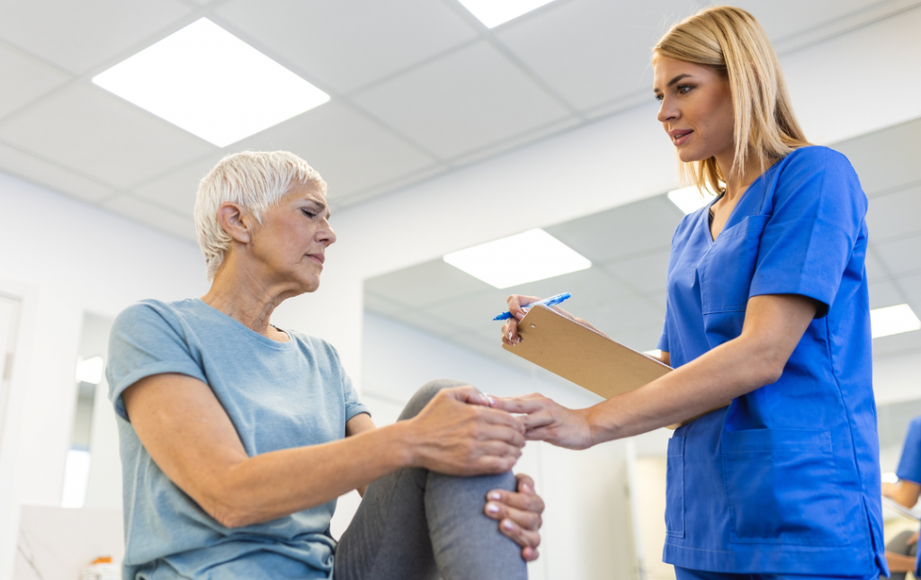 Older female patient holds her knee in pain during her appointment with a knee pain specialist.