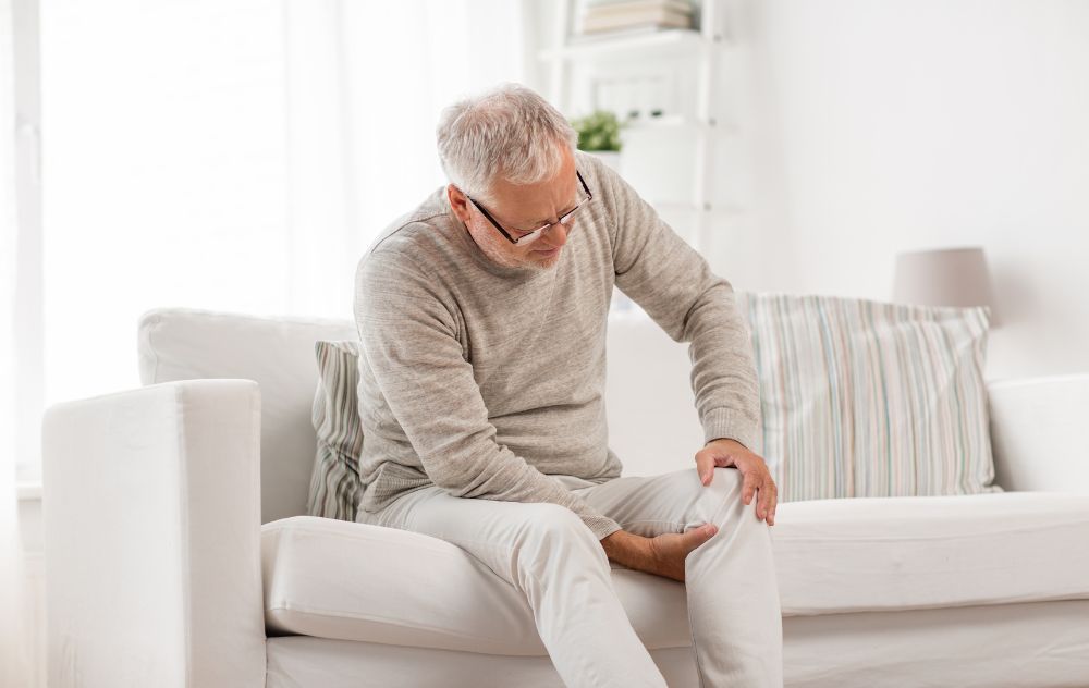 older adult holding knee while climbing sitting down